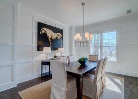 An all white dining room with a painting of a horse prominently displayed on one wall.